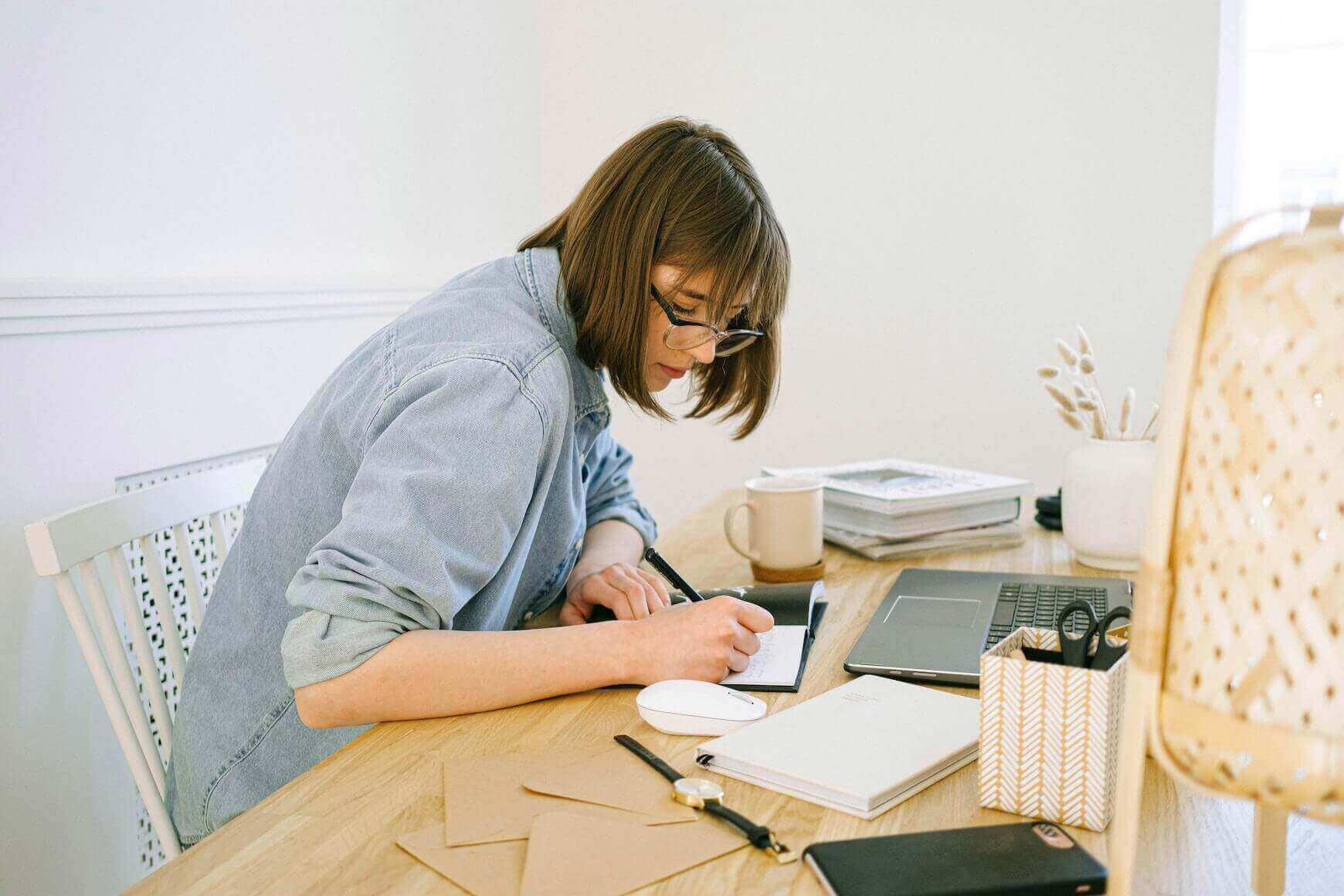 Fata in camasa albastra, aplecata deasupra unui caiet, la birou