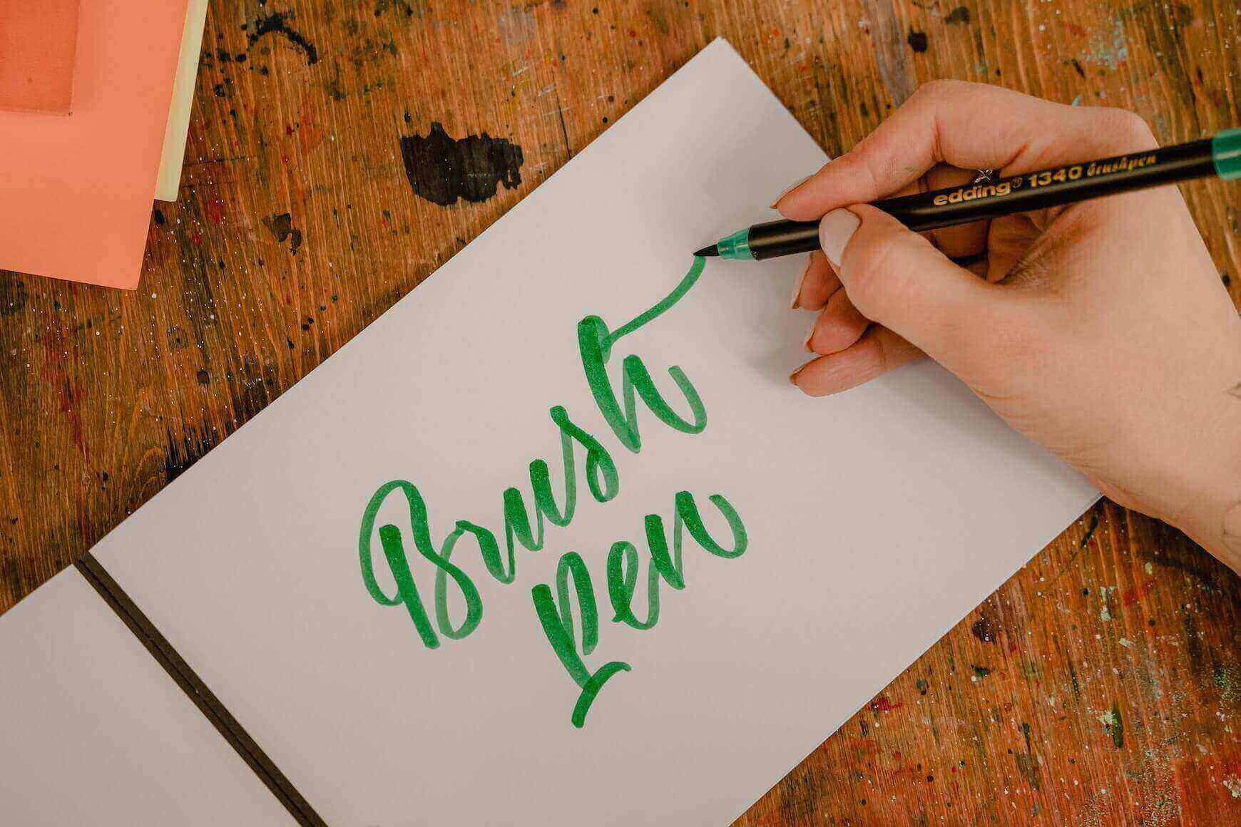 Textul brush pen scris cu verde pe o foaie alba cu un stilou pensula